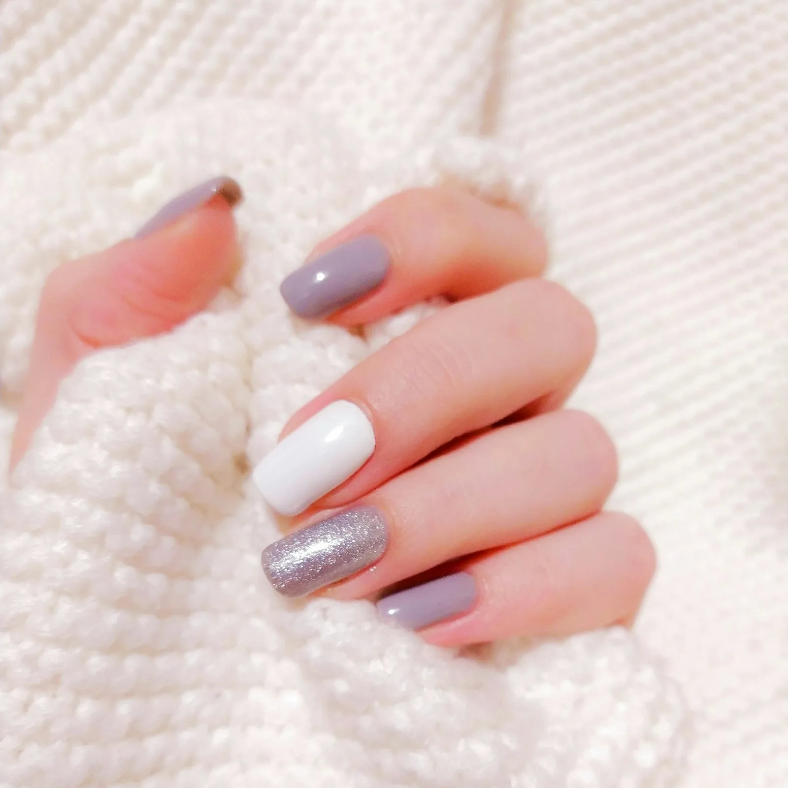 Manicura elegante en tonos suaves apoyada sobre lana blanca