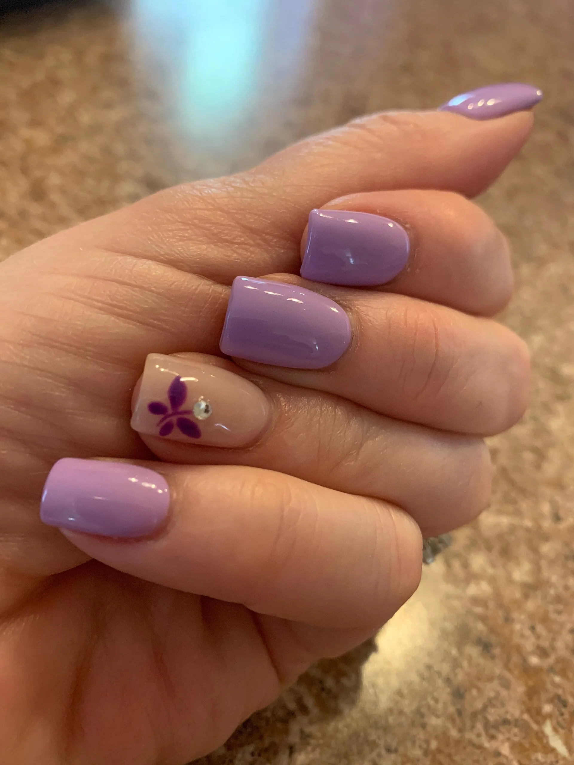 Manos con una manicura de diseño en tono lila